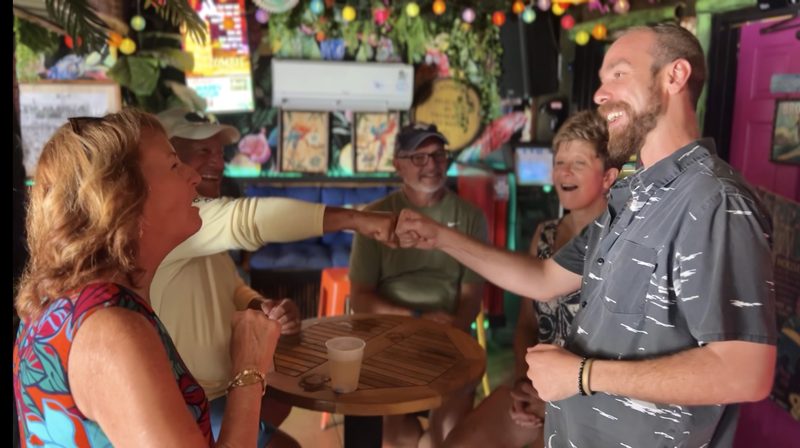Guide fist-bumping a guest at the string-lit Tiki House during the Key West cocktail crawl