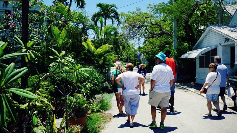 Tour group walking along a shaded, plant-lined lane in Old Town Key West
