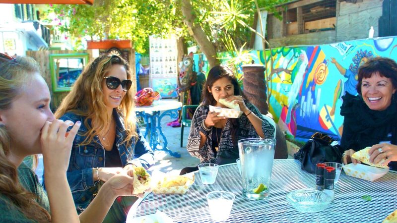Guests eating tastings at an outdoor table beside a brightly painted mural in Key West
