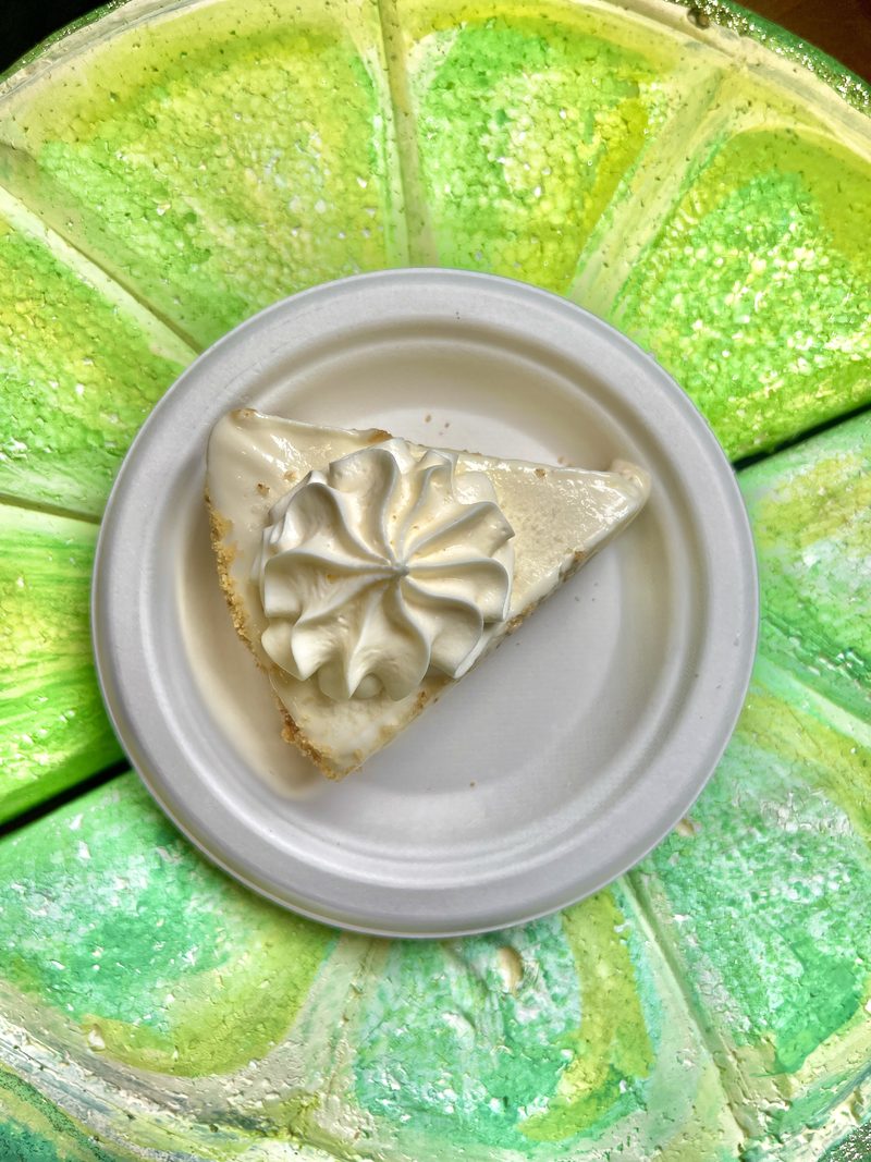 Overhead view of a slice of Key lime pie plated inside a bright green lime-shaped platter
