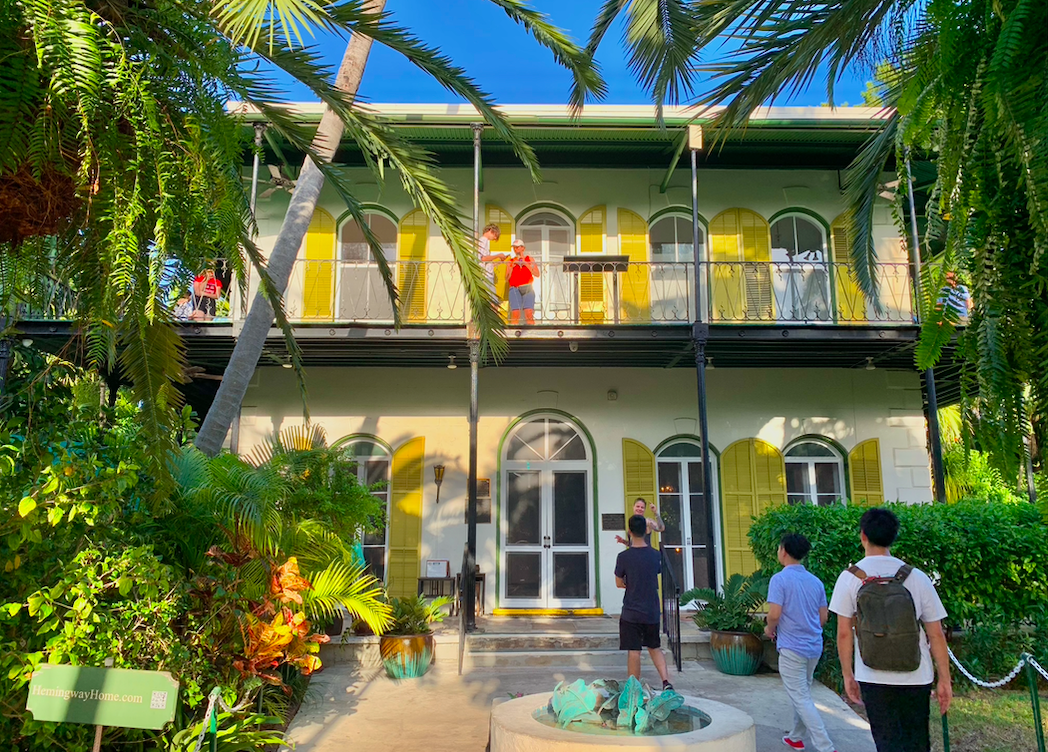 a group of people standing in a garden with Ernest Hemingway House in the background