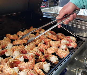 a man cooking hot dogs on a grill